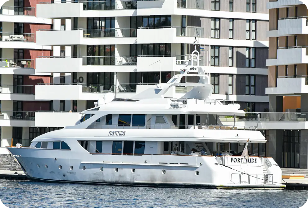 Een premium jacht afgemeerd in een chique stedelijke marina omringd door moderne residentiële architectuur.