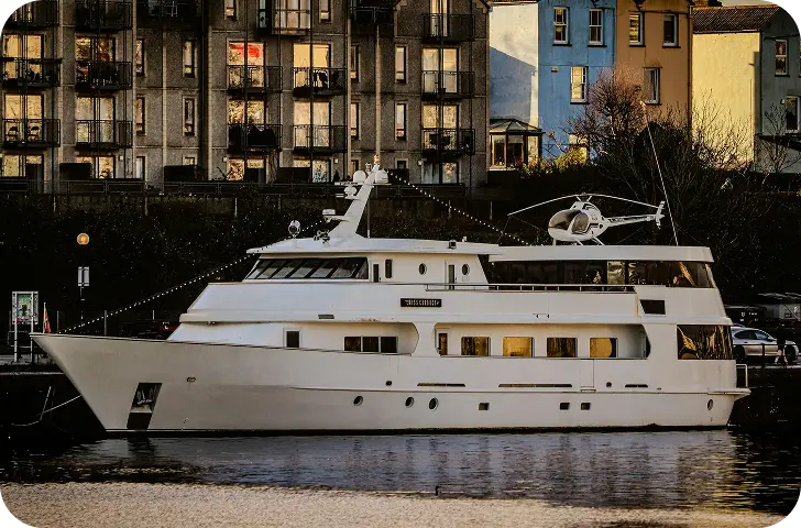 Een ruim jacht afgemeerd naast moderne appartementen langs een stijlvolle stedelijke waterfront.