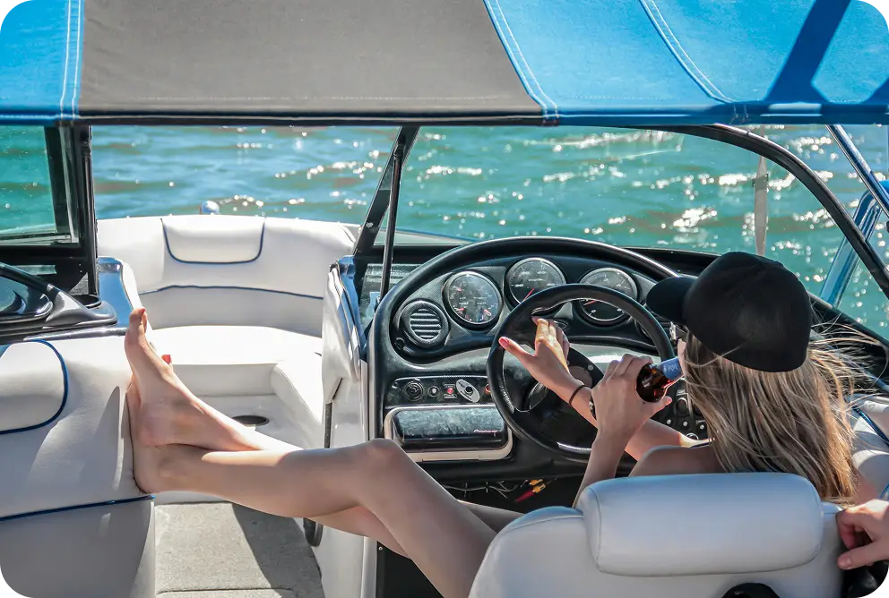 Een vrouw die geniet van een zonnige dag aan boord van een jacht terwijl ze zit nabij het stuurgebied met uitzicht op de oceaan om haar heen.