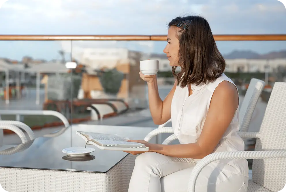 A woman enjoying a peaceful moment with a cup of coffee while overlooking scenic waterfront views.